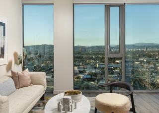 Living room at ARQ with floor-to-ceiling windows overlooking West Adams, Culver City, and the hills beyond at golden hour