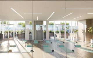 Light-filled yoga studio at ARQ with floor-to-ceiling glass, mirrored walls, and mats set up for yoga and Pilates, opening onto an outdoor fitness deck