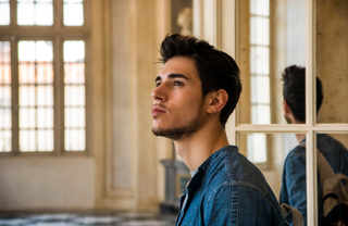Pensive young adult sits in grand room gazing upward