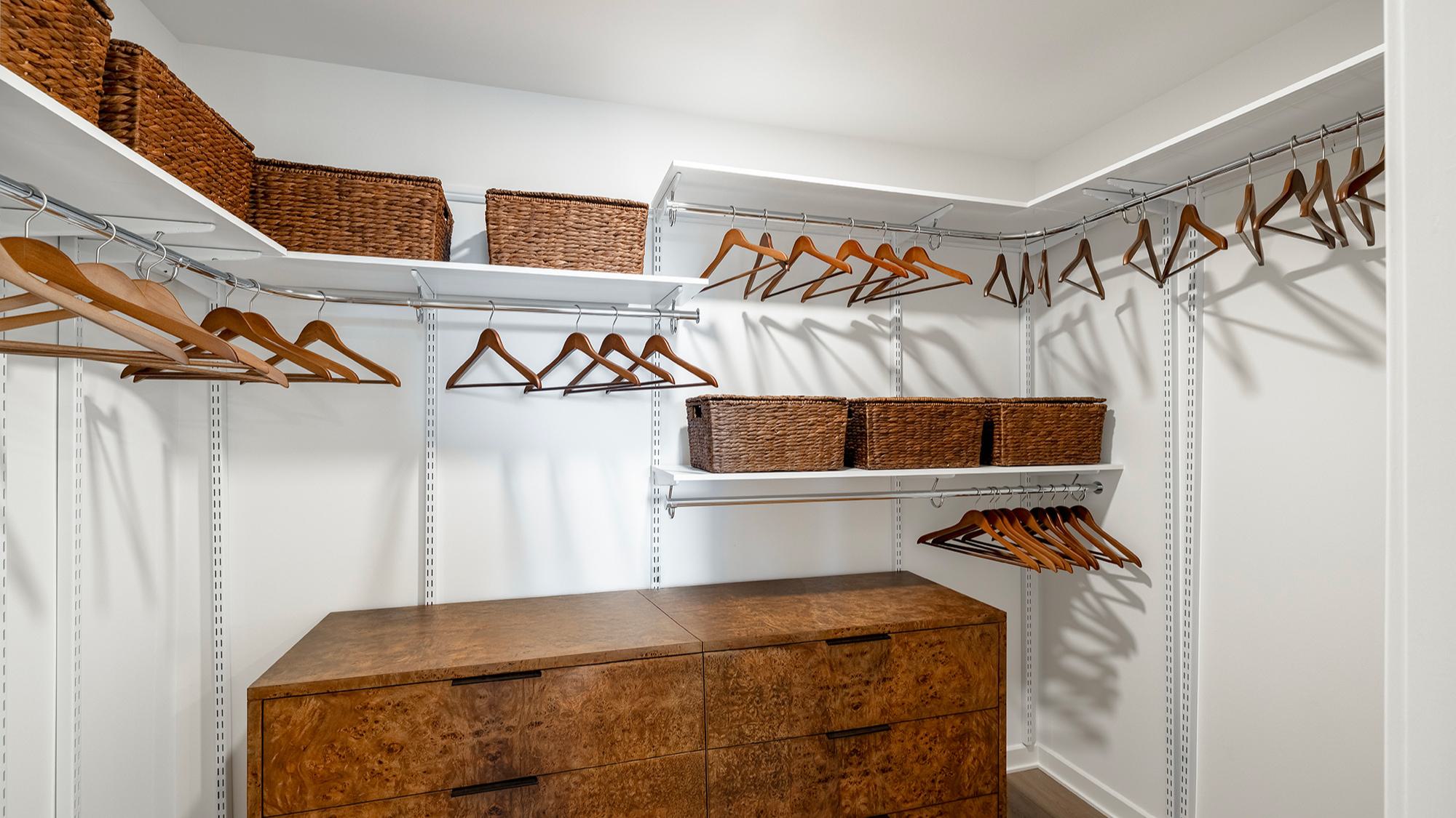 Large walk-in closet at Aerie with customizable shelving and double hanging areas, showcasing generous hanger space, open shelves, and room to incorporate a chest of drawers within the layout.