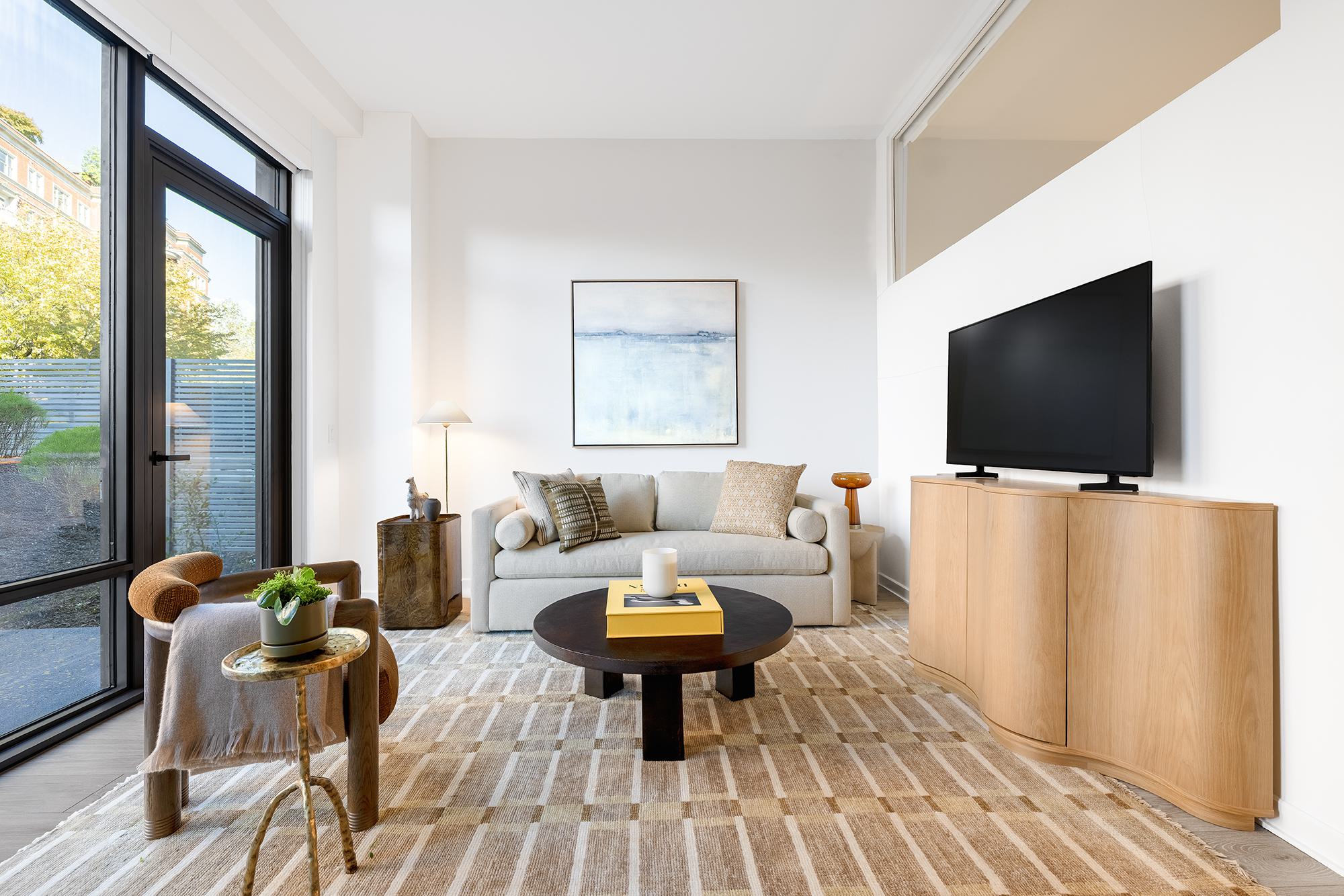 Zephyr living room with floor-to-ceiling glass doors opening to a private patio, creating seamless indoor–outdoor flow.