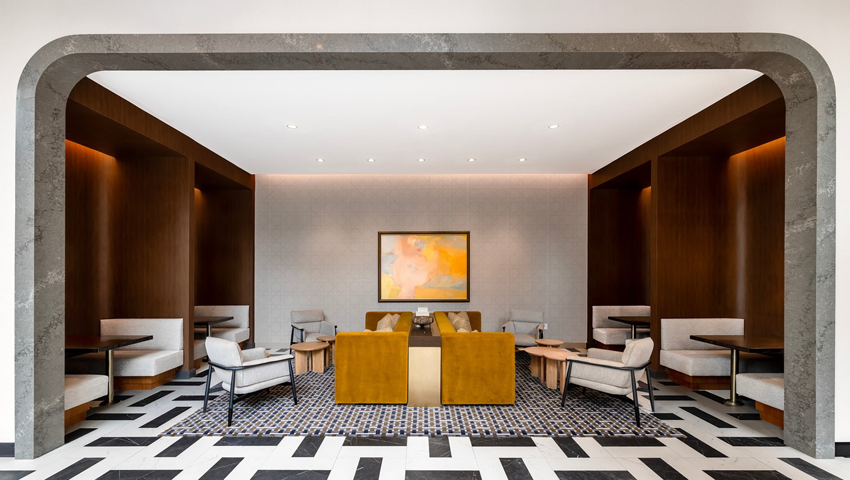 Coworking lounge at Zephyr with sculptural stone entry surround, wood-paneled walls, built-in banquettes, lounge seating, and recessed lighting.