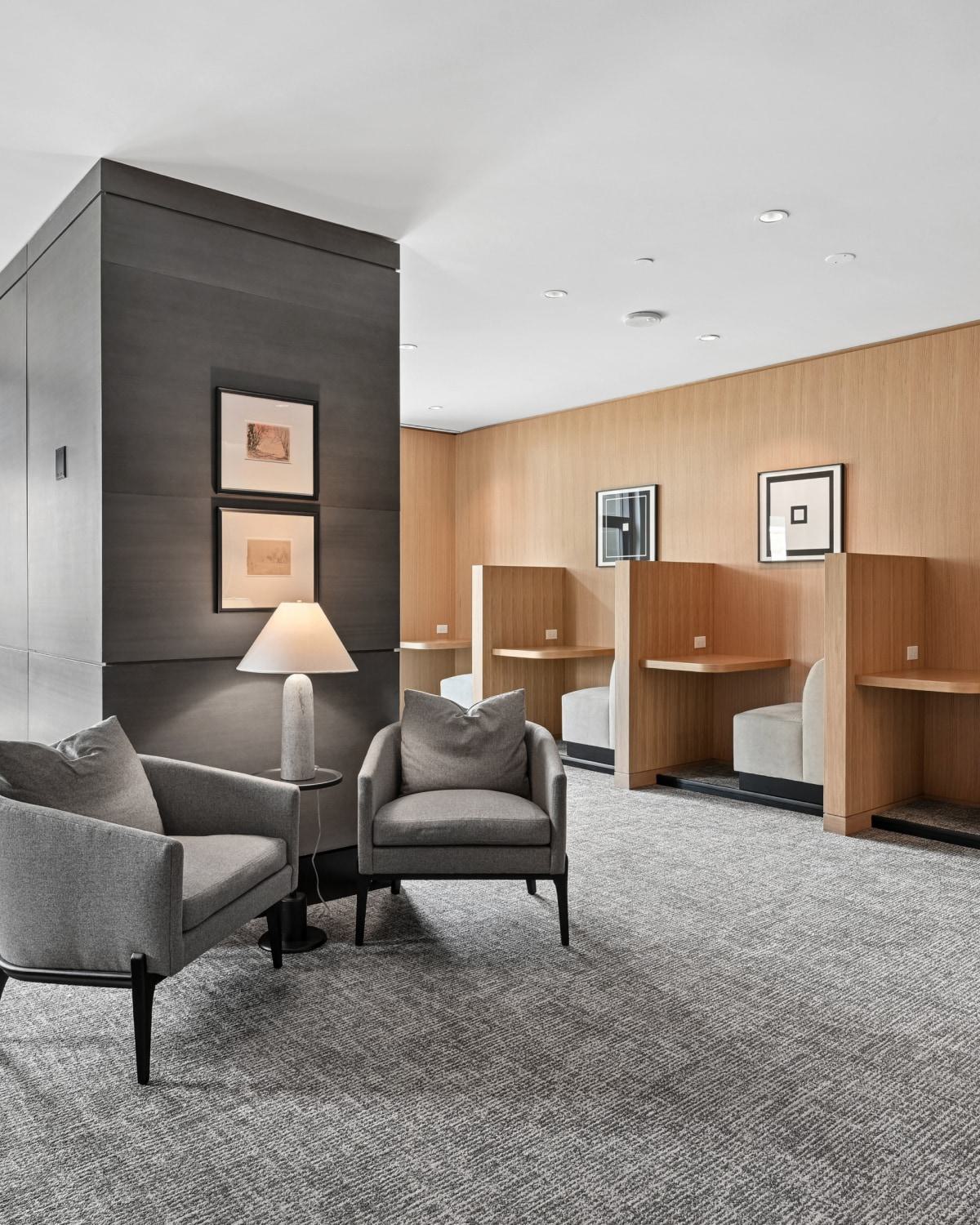 Resident co-working space at Avant Reston featuring individual wooden study booths and grey armchairs.