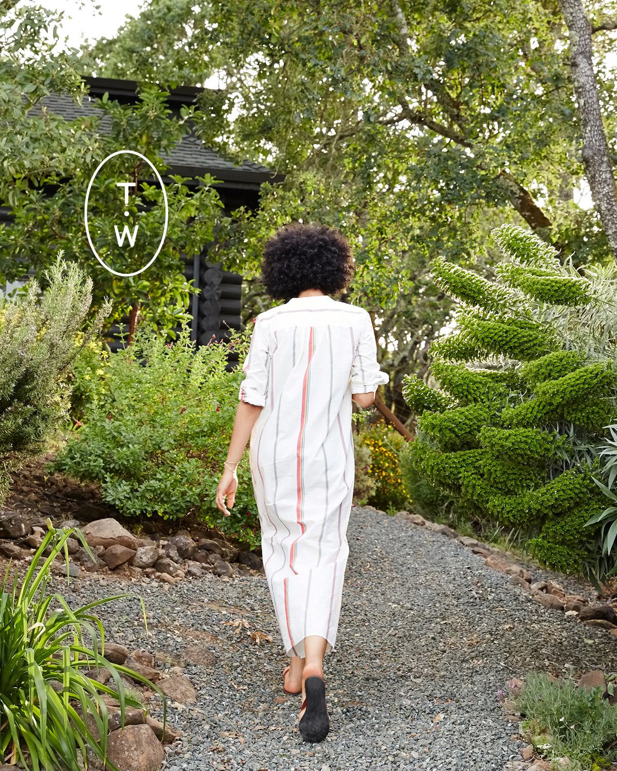 Woman walking on path surrounded by lush landscape