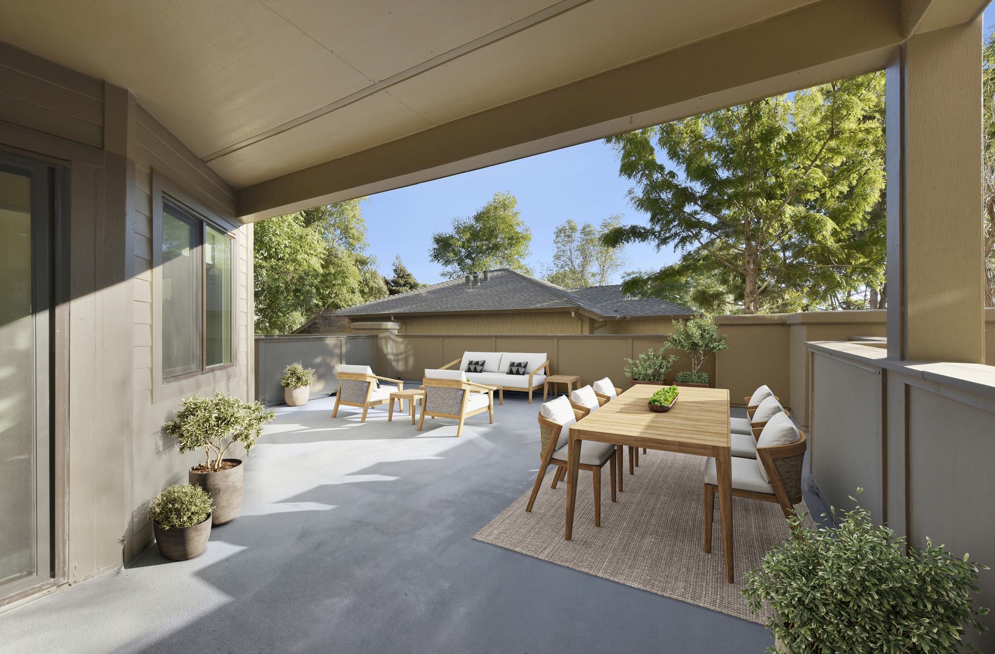 A spacious, modern outdoor patio featuring a wooden dining table with chairs and a separate lounge seating area with a sofa and armchairs.