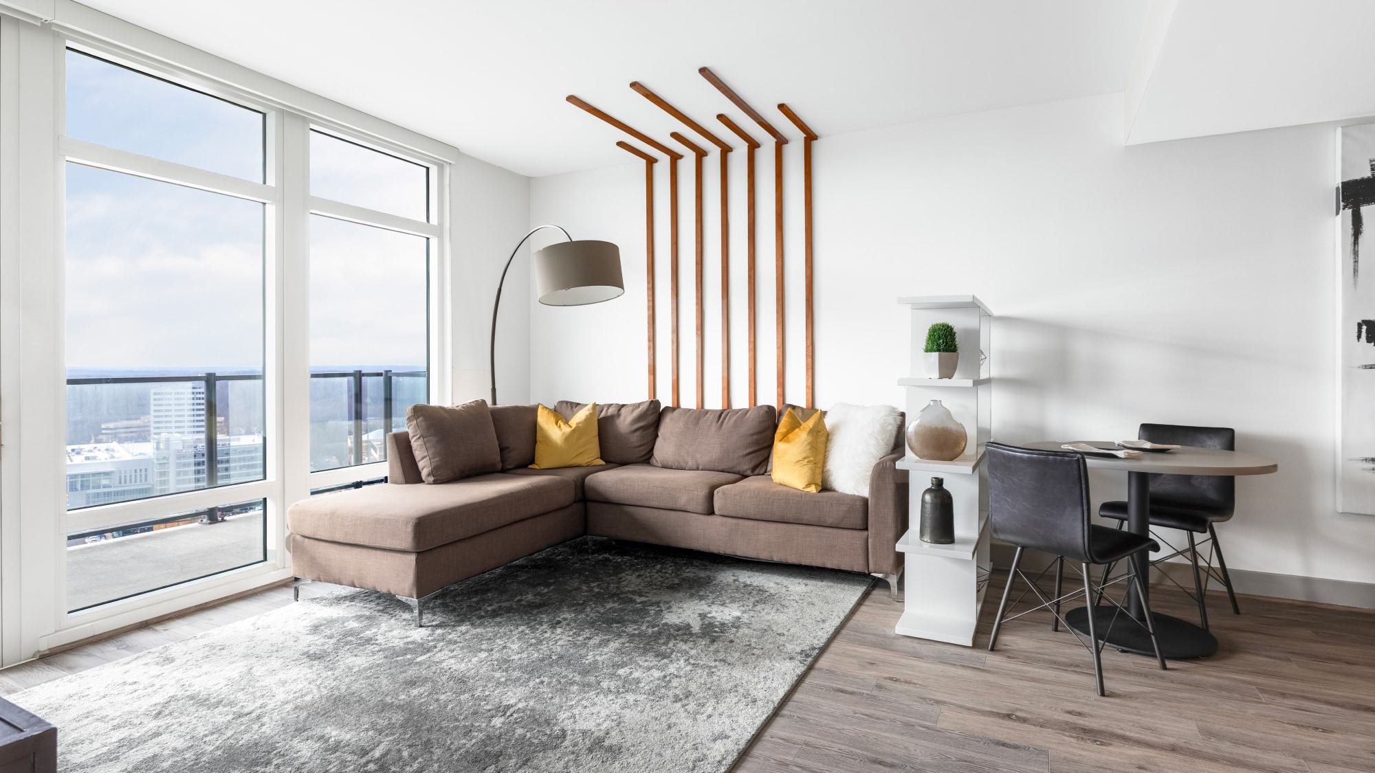 Modern high-rise apartment living room with floor-to-ceiling windows, expansive Tysons views, contemporary furnishings, and abundant natural light.