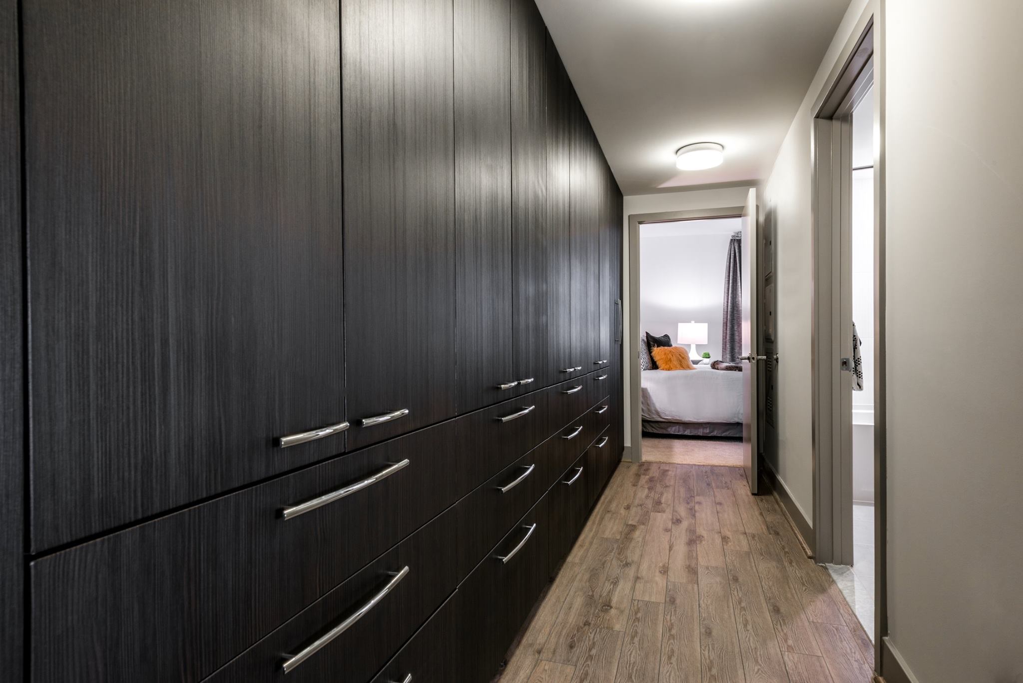 Extended built-in wardrobe with multiple drawers and cabinetry leading toward bedroom in luxury apartment at Adaire.
