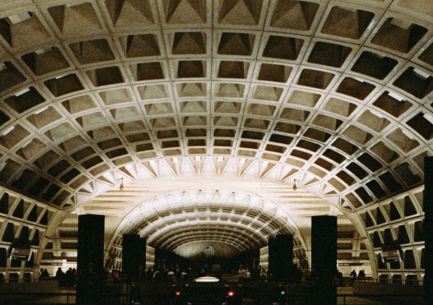 Federal Center SW Metro station platform with vaulted coffered concrete ceiling, arched lighting, and train arriving below in Washington, DC.