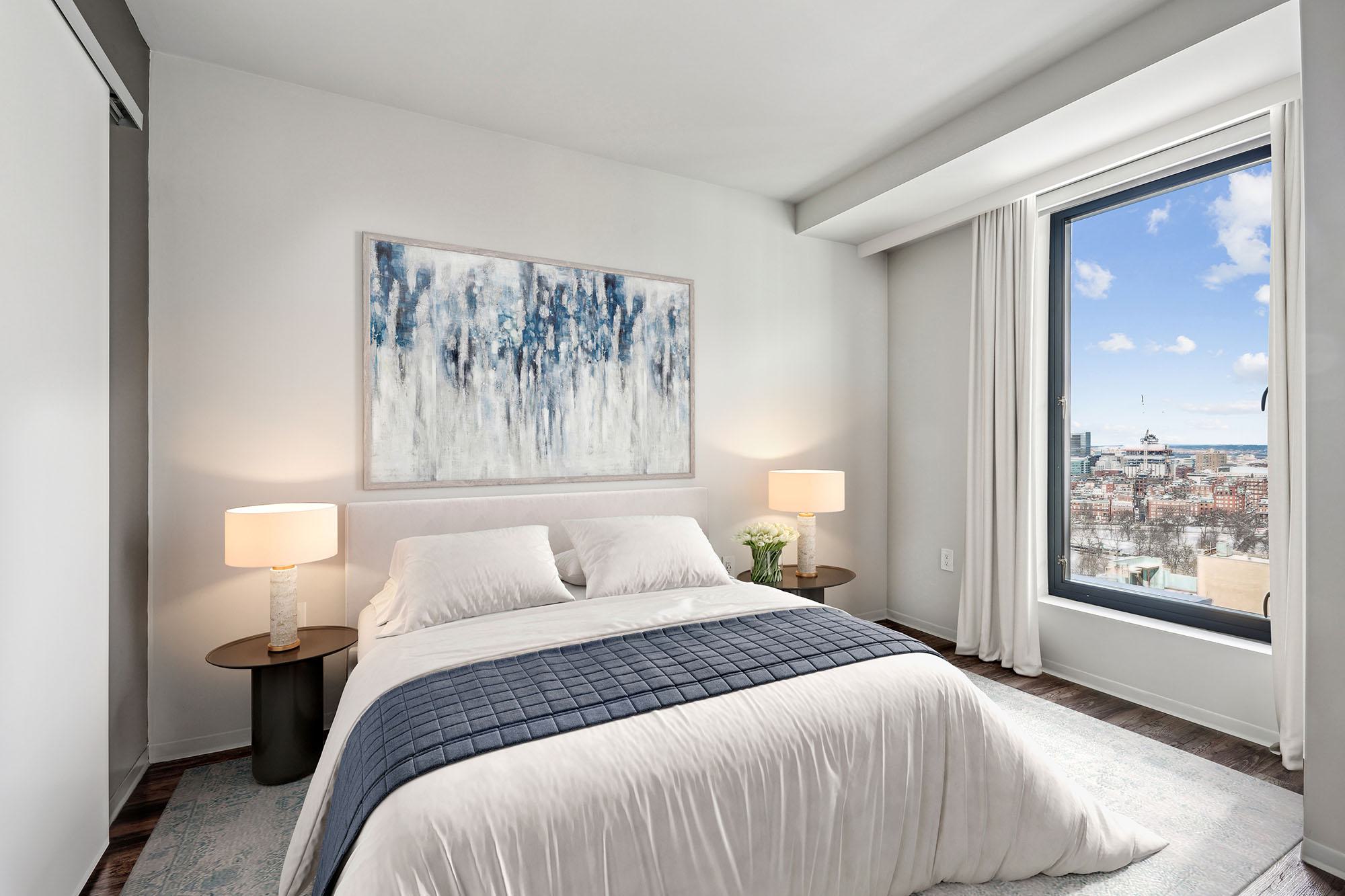 Bedroom at Luka on the Common with large window overlooking Boston skyline and treetops of Boston Common.