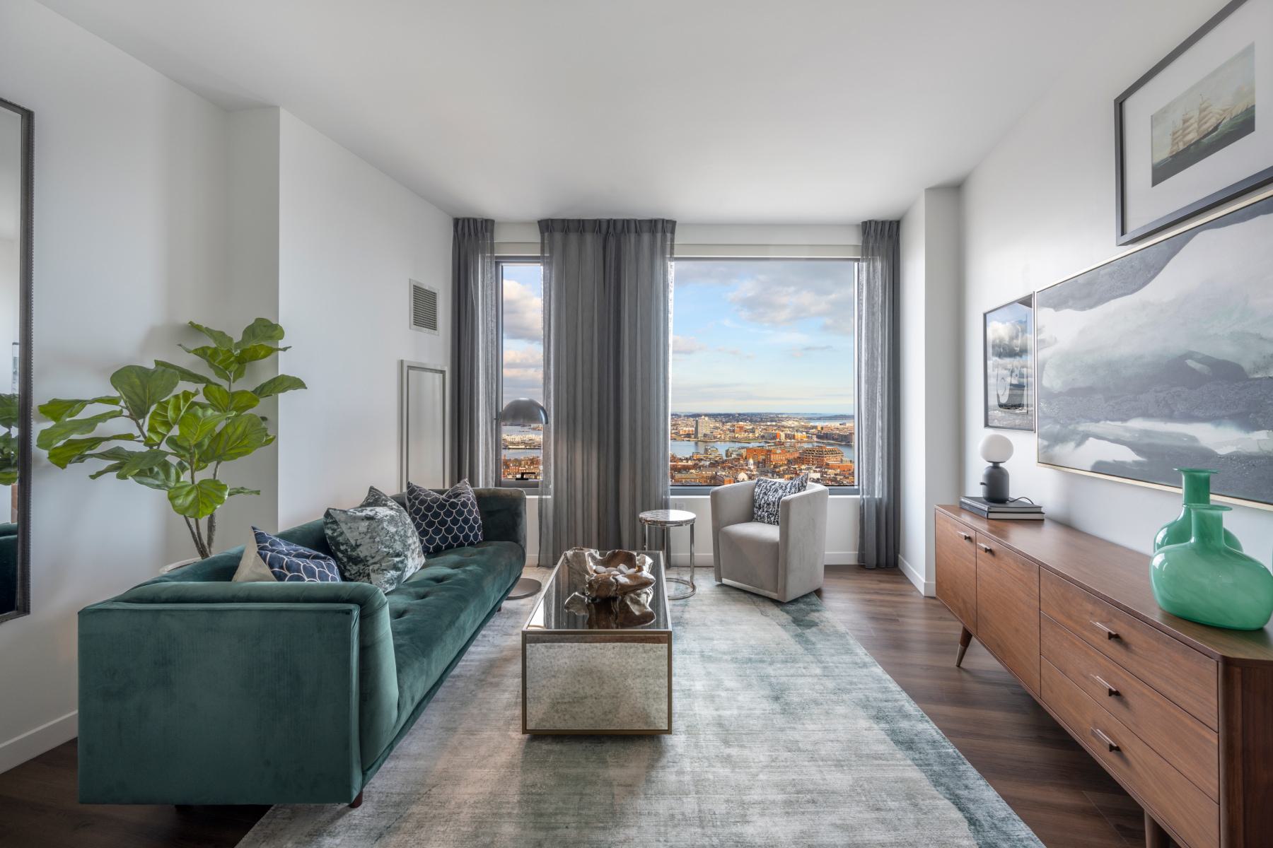 Bright living room with large windows framing Boston skyline and harbor views.