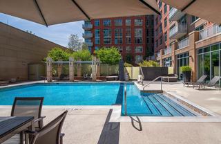 Outdoor pool deck at Avant Reston with swimming pool, lounge chairs, shaded seating areas, and courtyard views surrounded by the apartment building.