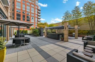 Outdoor courtyard dining area at Avant Reston with shaded tables, grill station, pergola seating, and landscaped terrace.