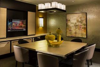 Private meeting room at Avant featuring a large conference table, upholstered chairs, wall-mounted display screen, modern pendant lighting, and built-in cabinetry.