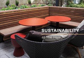 close-up view of a lush outdoor courtyard at The Hale featuring a sustainable design with built-in wooden bench seating, two vibrant red circular bistro tables, and modern woven lounge chairs with plush cushions. The background shows manicured greenery and shrubs, while the foreground has a "Sustainability at The Hale" graphic overlay.