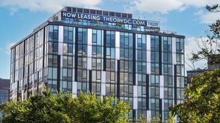 Exterior view of Theory apartments in DC's Union Market District, showing the modern glass architecture, rooftop lounge, and proximity to trees and parks.