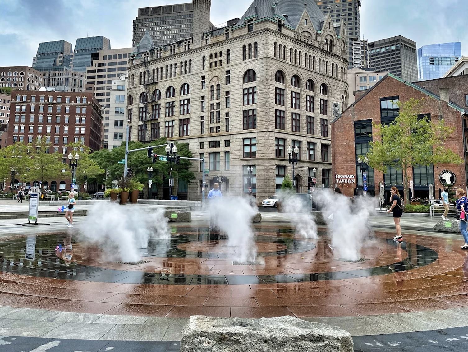 Summer in Downtown Boston: The Rings Fountain misting station on the Greenway with the historic Granary Tavern and city skyscrapers in the background.