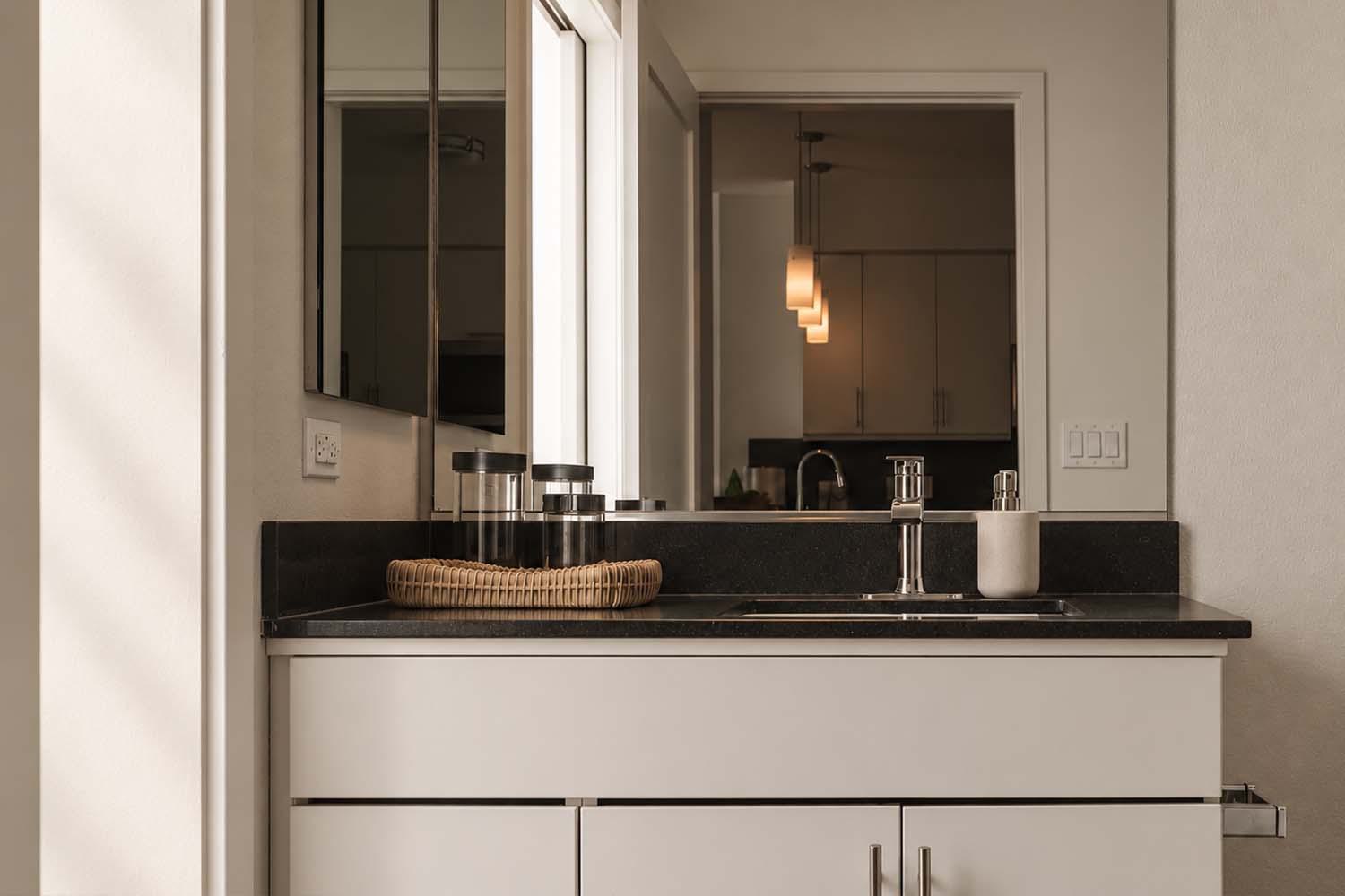 Styled kitchen counter with black quartz countertop, tile backsplash, open cookbooks, and utensils.