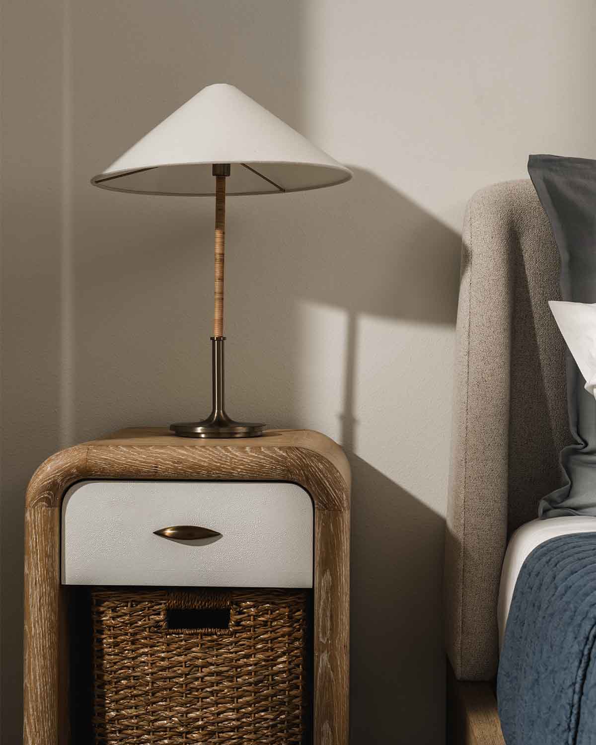 Refined, stylish bedside setup with a modern cone lamp, wooden nightstand, and upholstered headboard.