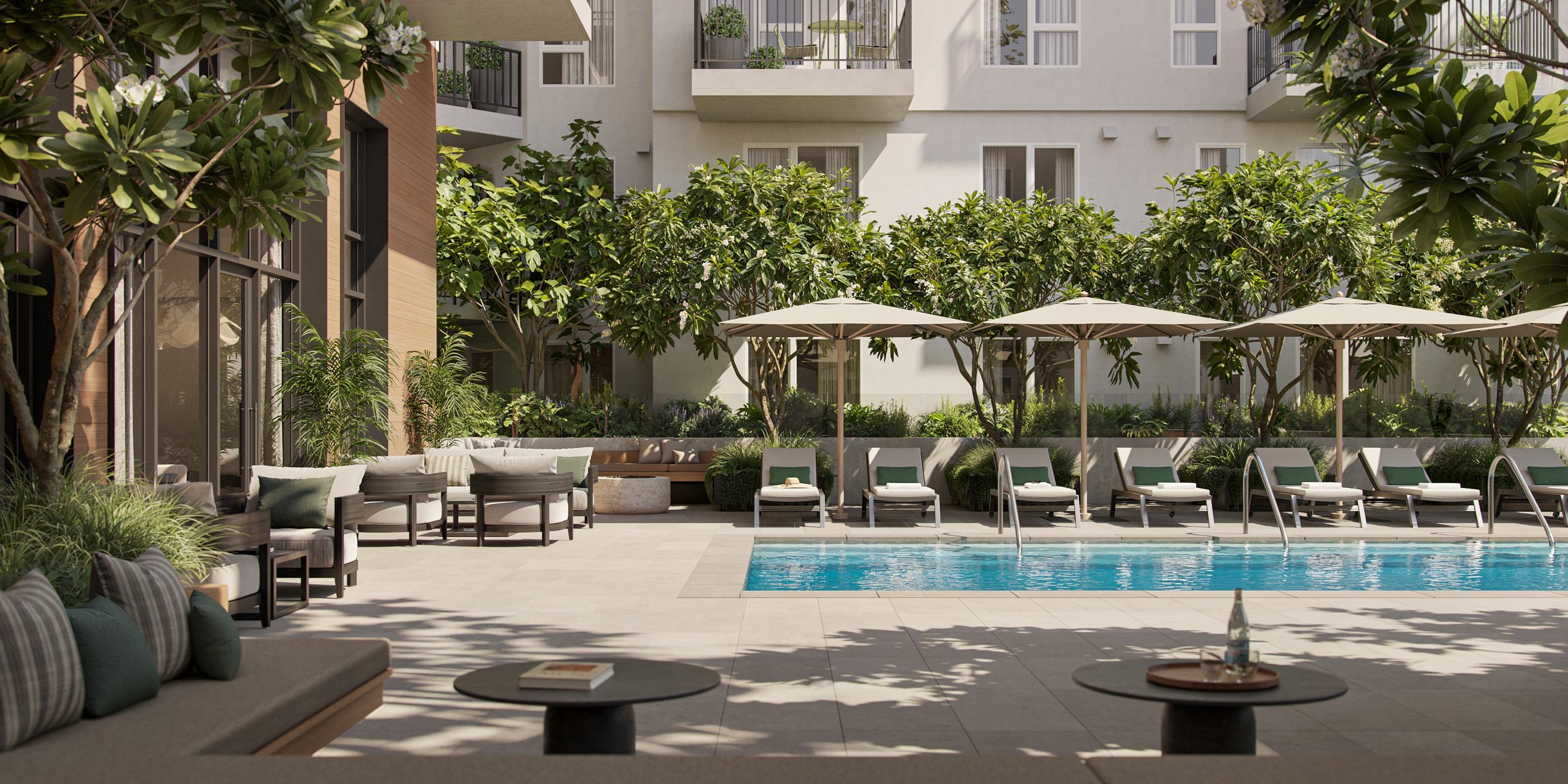 Outdoor swimming pool deck at Maris surrounded by sun loungers, umbrellas, lush trees, and a shaded lounge area.