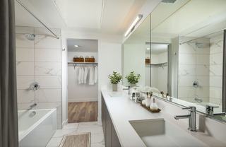Modern luxury bathroom at VOX featuring a double vanity and a large en suite walk-in closet with built-in shelving.