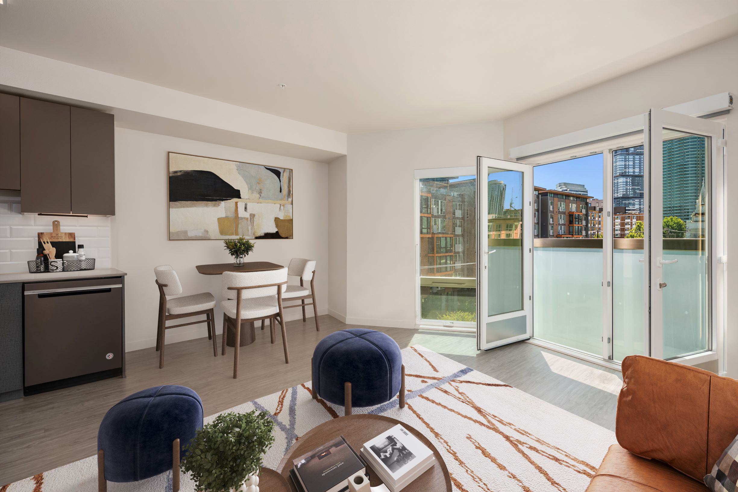 Sunlit apartment living room with open French doors to a Juliet balcony, overlooking South Lake Union buildings.