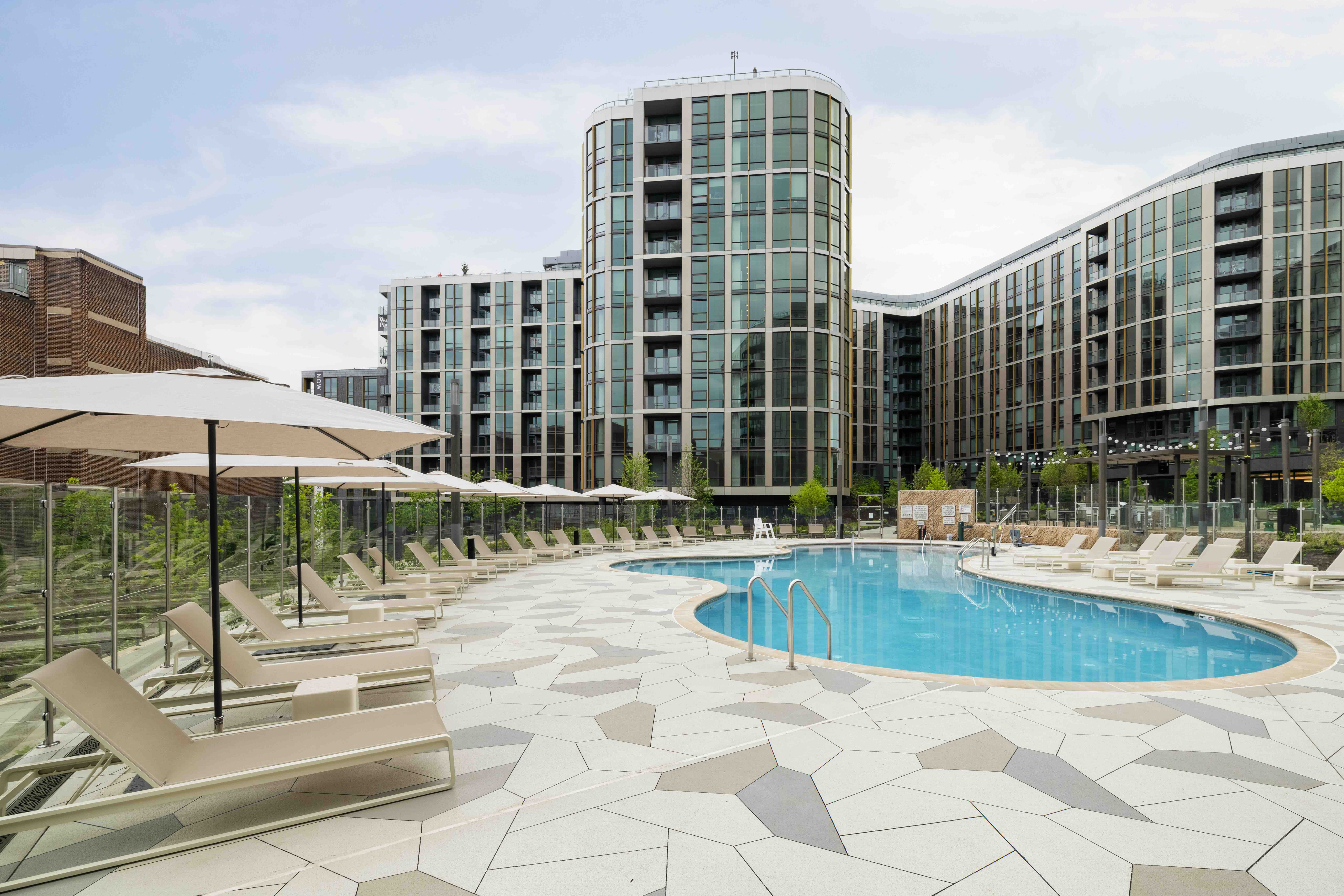 ows of low-profile chaise lounges and minimalist market umbrellas lining a stone pool deck.