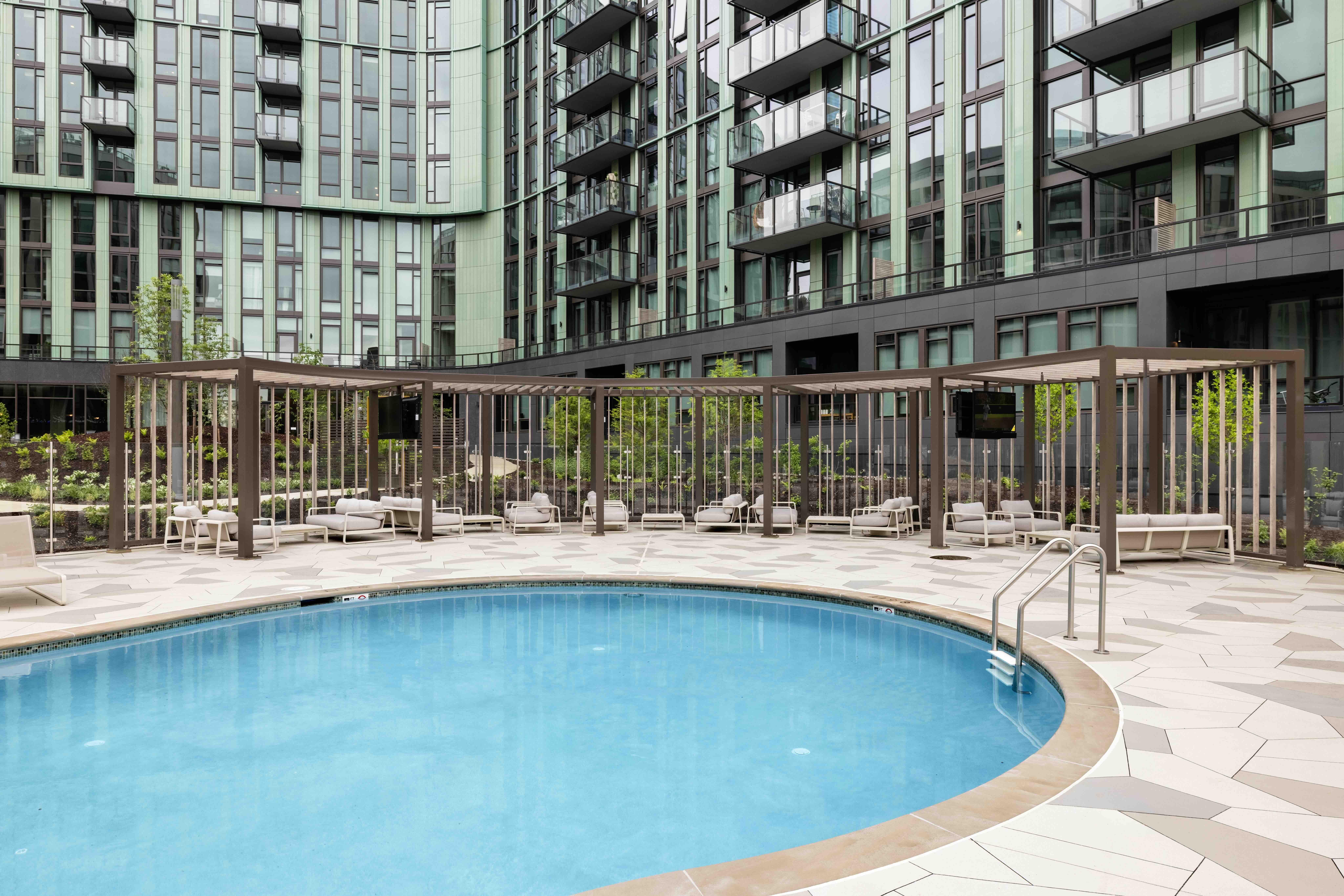 A slatted timber pergola over a poolside lounge area with premium outdoor seating.