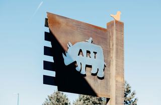 Iconic Rino Denver corrugated metal sign with Rhinoceros icon, the word "Art", and a tiny bird sitting on top of the Rhino.