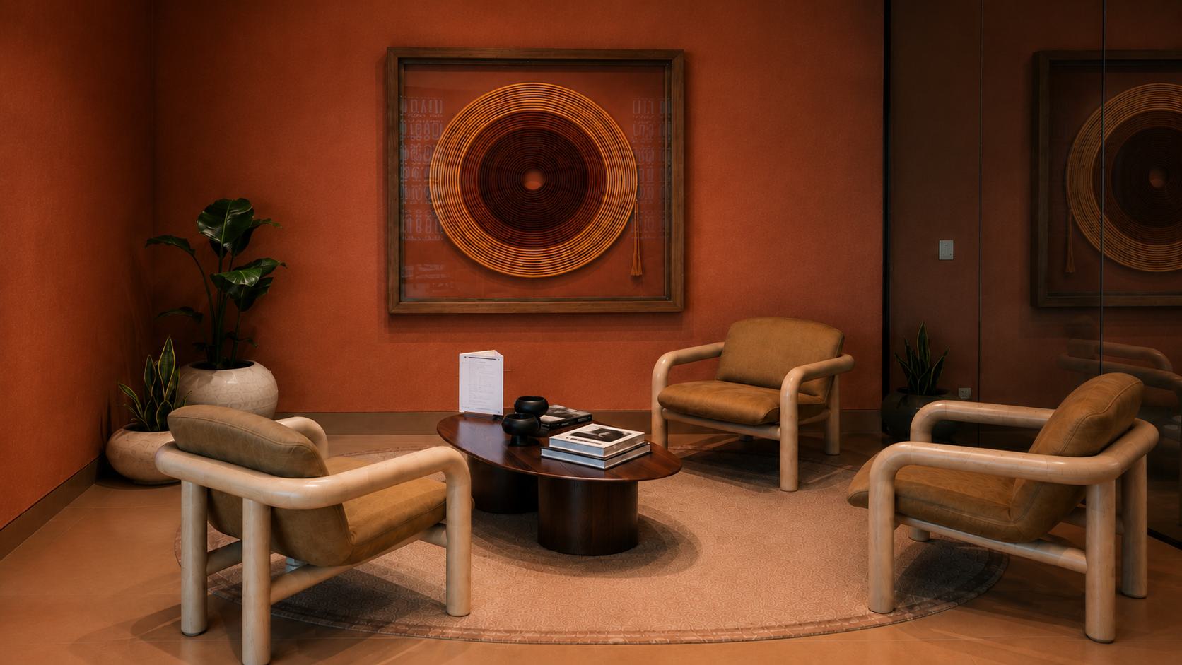Warm terracotta lounge with a framed gold and brown circular fiber artwork.