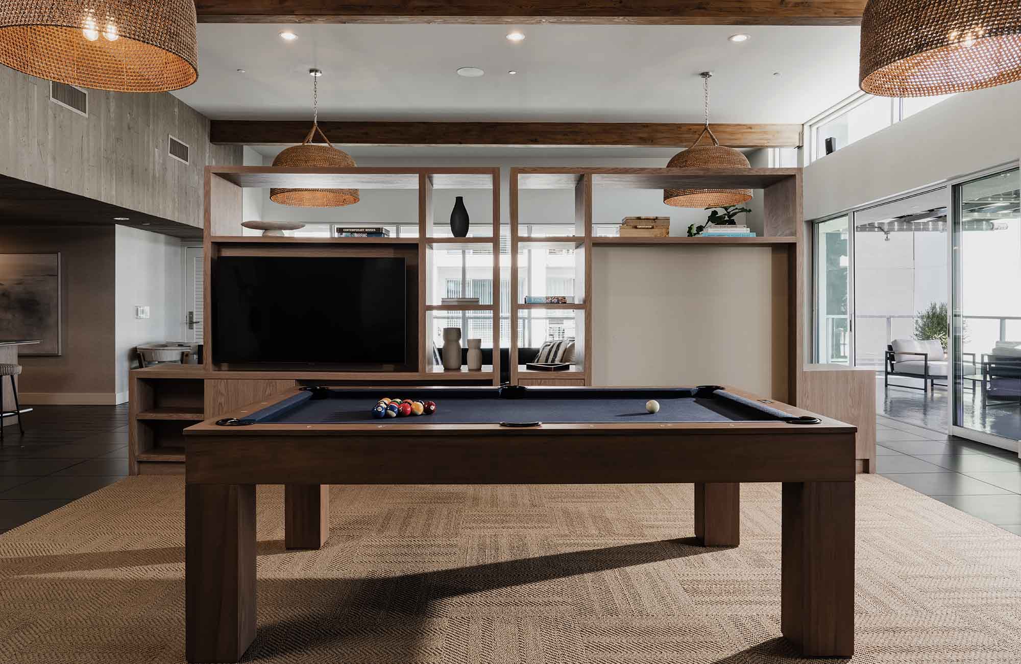 Custom wooden pool table in the sky lounge at Stella Apartments in Marina del Rey with television and built-in shelving.
