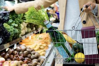 woman in grocery store product aisle w basket