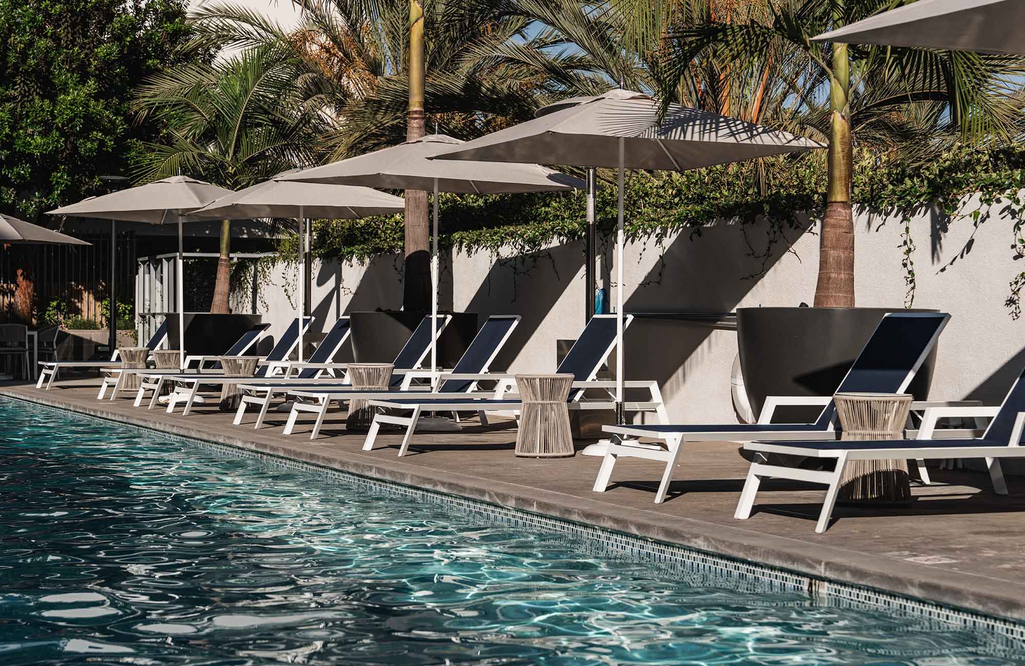 Heated outdoor saltwater pool lined with chaise lounges and umbrellas at Stella's retreat.
