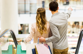 A couple with shopping bags going down an escalator