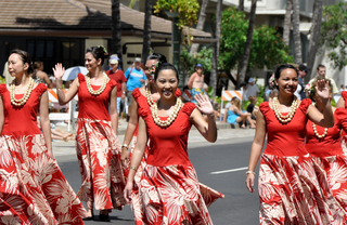 Woman in red dresses in a street parade waving toward the crowd