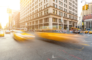 Taxis moving quickly down upper east side streets at sundown