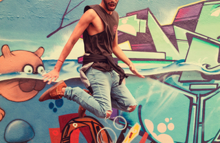 A person jumping in front of a graffiti style wall mural