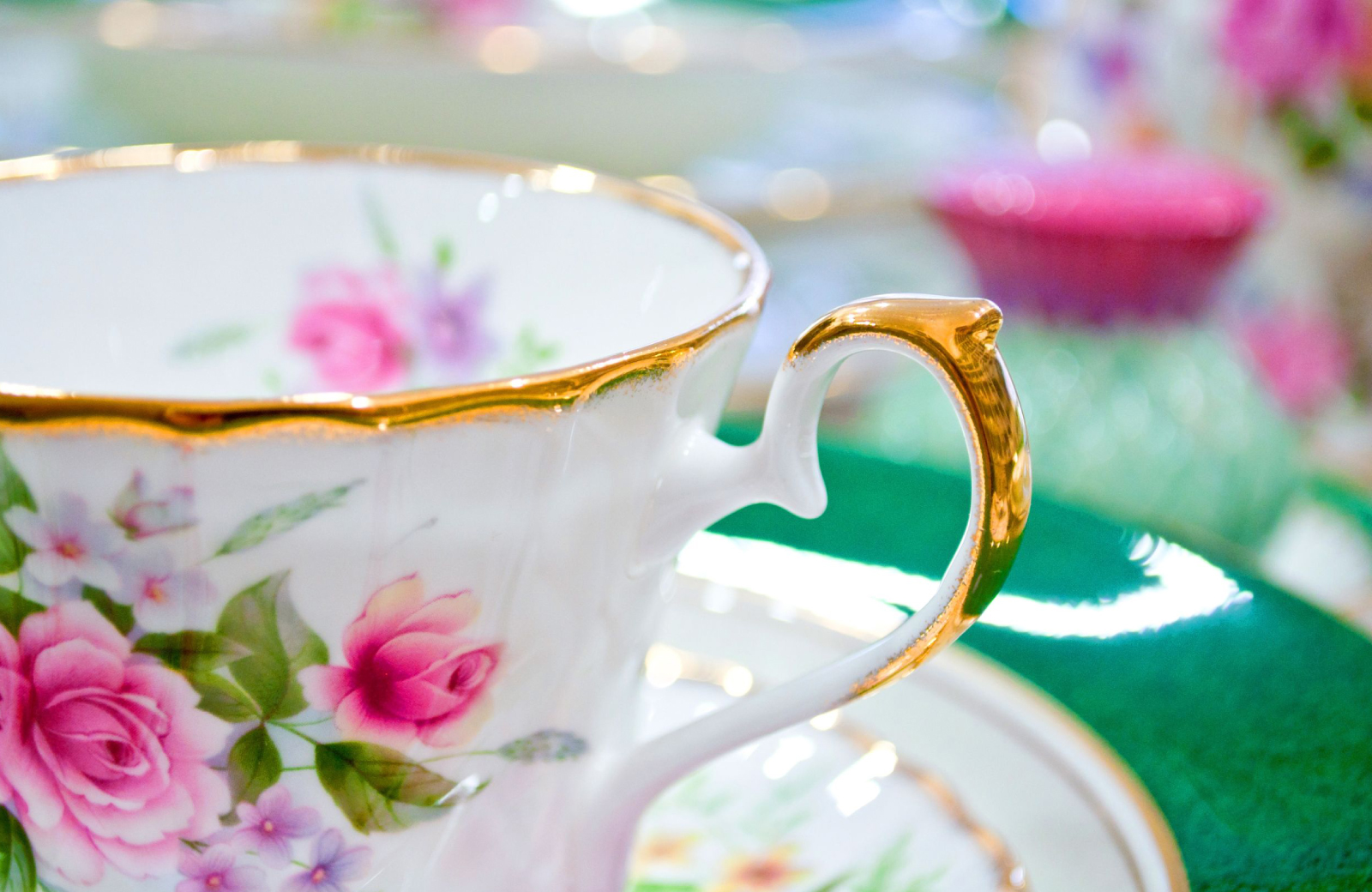 white teacup with pink roses - hosting a tea party - The Vue