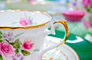 white teacup with pink roses - hosting a tea party - The Vue