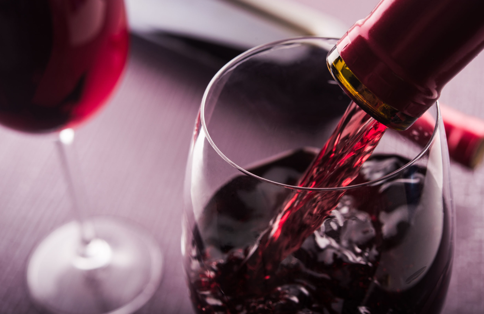 a close up of a bottle of red wine pouring into a wine glass - The Waypointe Apts