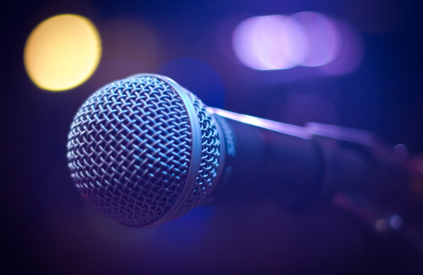 a close up of a karaoke Microphone with blue & yellow lights in the background