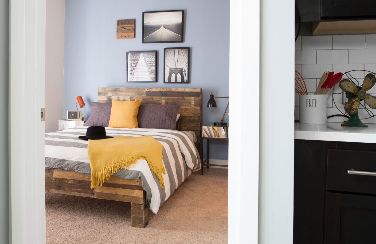 a bed with wooden slat headboard and grey & white comforter with a yellow throw blanket & yellow pillow on bed