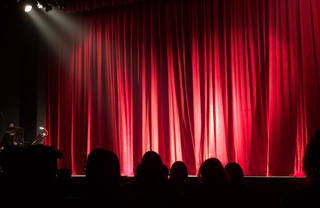 Silhouette of people in a theater before curtains open