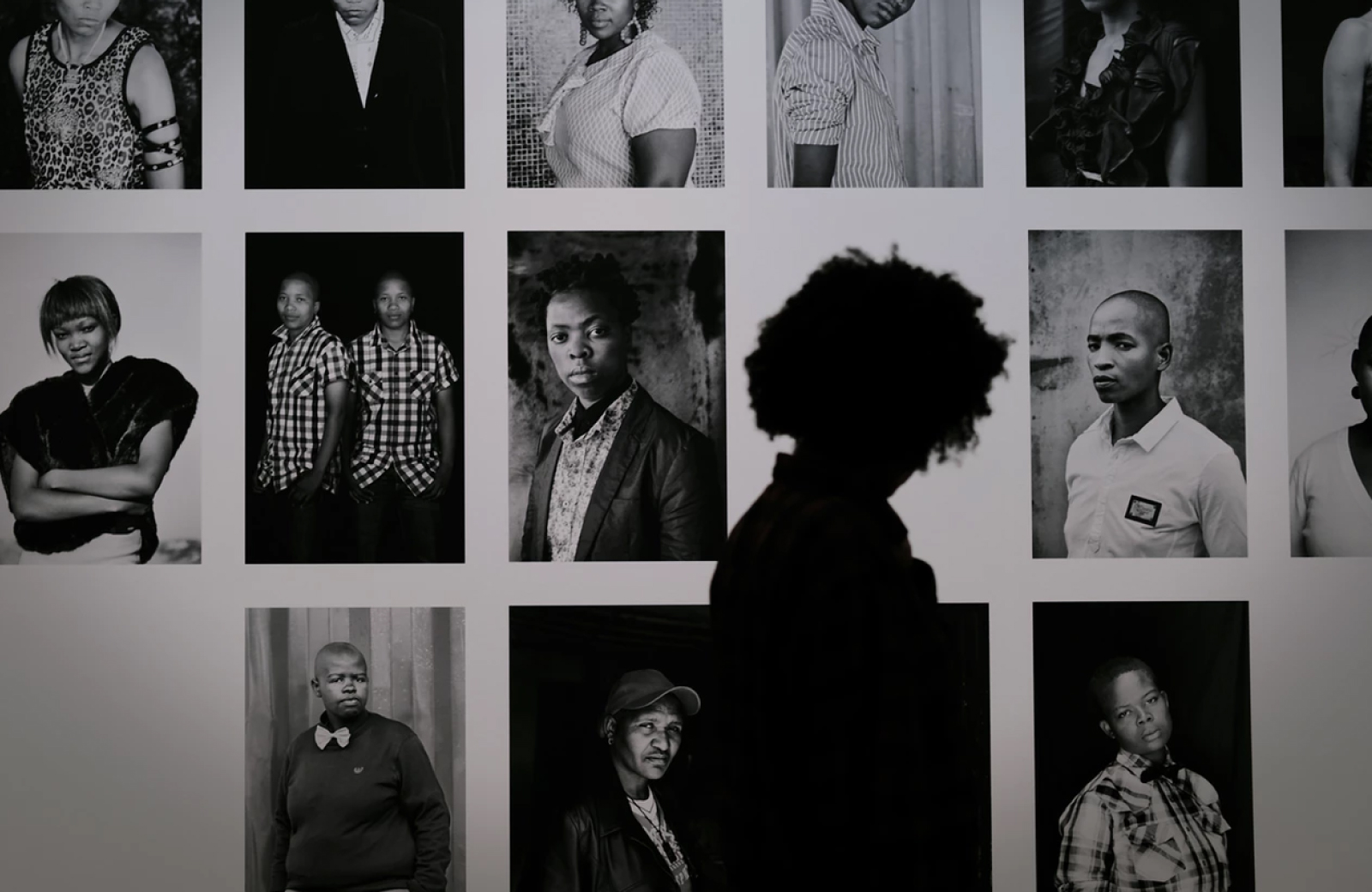 silhouette of a person standing in front of a wall of black and white photos at paul getty museum in LA - The Madrid