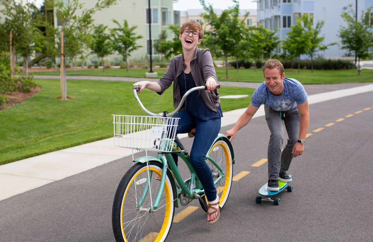 Girl on Bike Pulling Guy on Skateboard