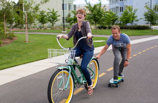 Girl on Bike Pulling Guy on Skateboard