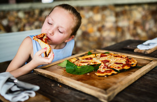 Young girl eating pepperoni pizza at a restaurant.