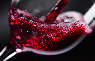 A close up of red wine pouring into a glass
