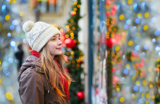 Woman wearing a beanie and scarf looking at Christmas trees.