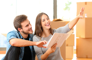 Couple inspecting documents, surrounded by moving boxes