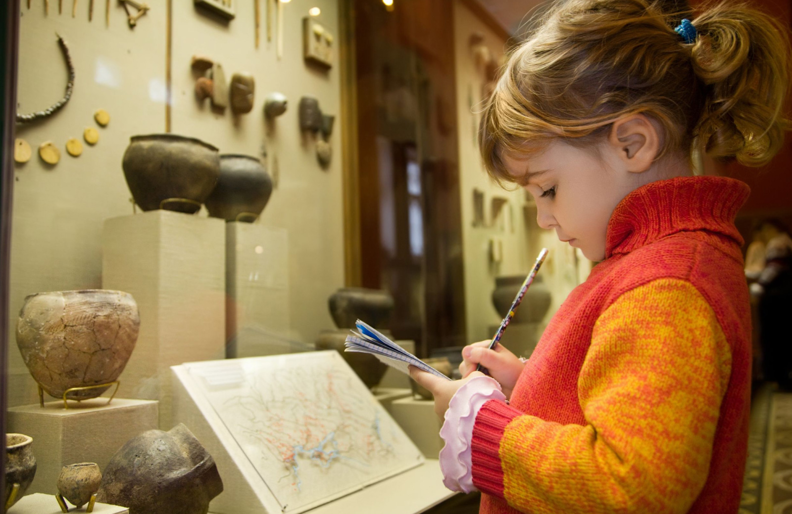 girl taking notes on antique exhibit